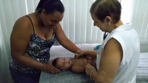 O pequeno Enzo Nunes é examinado pela Dra. Maria Cristina A. Fuser na UBSF Serradinho e a mãe Sueli recebeu orientações da médica. (Foto: SESAU)